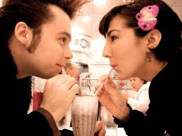 A couple drinking from same glass
